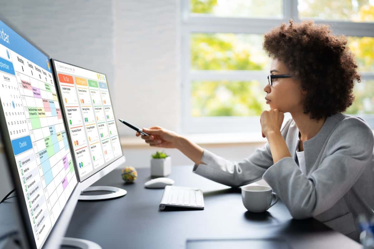 Loan officer reviewing a color-coded loan pipeline on dual monitors