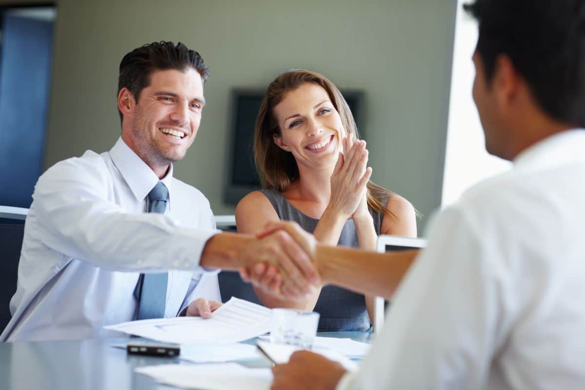 Lender shaking hands with a client across a table